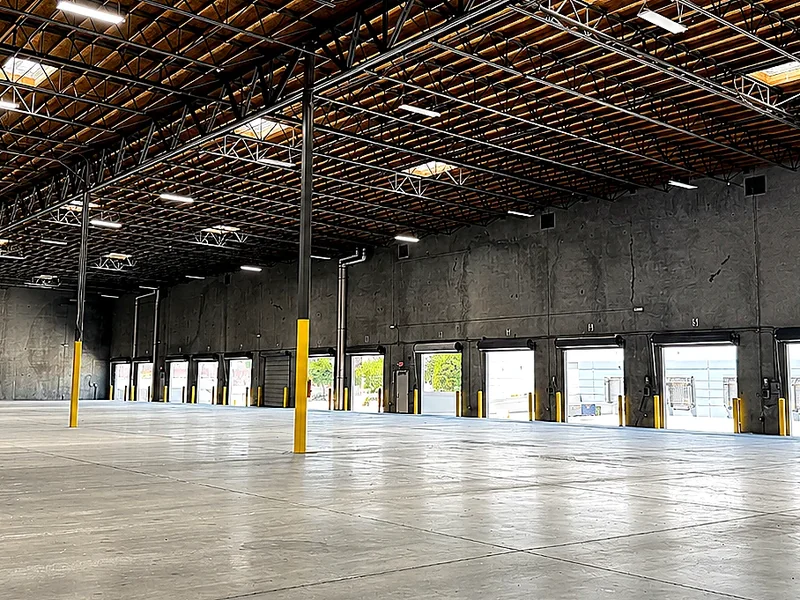 Vacant industrial warehouse interior with high ceilings, concrete floors, and multiple loading docks